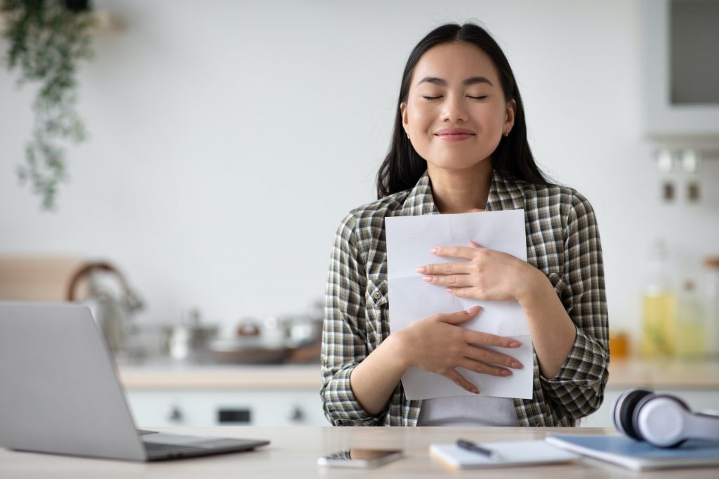 Delighted young asian woman student reading invitation letter